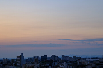 都市の夜明け。東の空が明るくなり雲がまだ昇る前の太陽に照らせら美しいグラデーションを見せる。神戸市内から大阪方面を臨む。