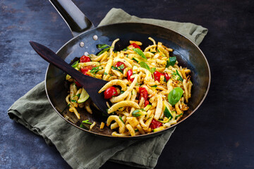 Traditional fried Austrian schupfnudeln with vegetables and herbs as a vegetarian dish served as a close-up in a rustic pan