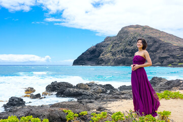 Teen girl in purple dress on Hawaiian coast