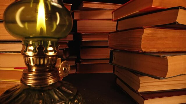 Gas lamp near stack of old books, slider footage in antique shop, bookstore.