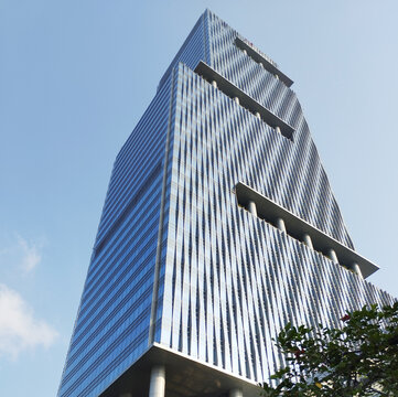 Glass-paneled office building. The glass is blue. Sky background. View from below.