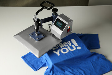 Printing logo. Heat press with blue t-shirt on white table