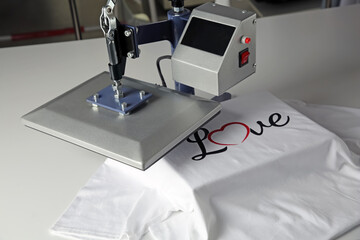 Printing logo. Heat press with t-shirt on white table
