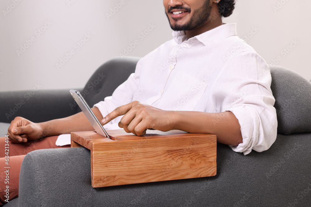 Canvas Prints Man using smartphone on sofa armrest wooden table at home, closeup