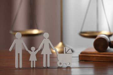 Family law. Figure of parents with children, scales and gavel on wooden table, space for text