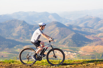 Fototapeta na wymiar Cyclist riding a mountain bike down a trail with mountains in the background