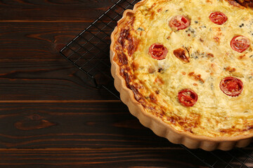 Delicious quiche with cheese and tomatoes on wooden table, closeup. Space for text