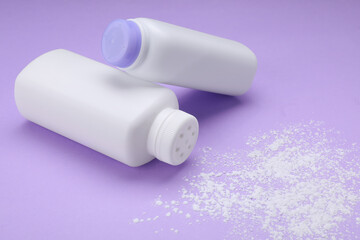 Bottles and scattered dusting powder on violet background. Baby cosmetic products