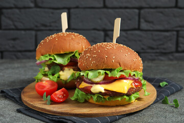 Delicious burgers with beef patty and tomatoes on grey table