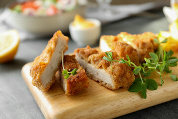 Delicious cut schnitzel served with microgreens on grey table, closeup
