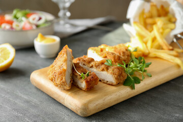 Delicious cut schnitzel served with microgreens on grey table