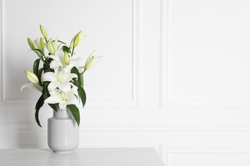 Fototapeta na wymiar Beautiful bouquet of lily flowers in vase on light table near white wall, space for text