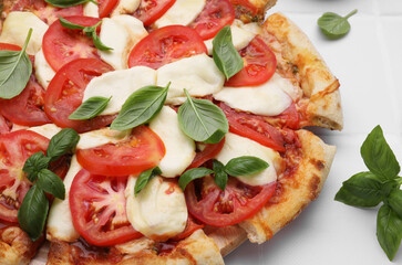 Delicious Caprese pizza with tomatoes, mozzarella and basil on white table, closeup