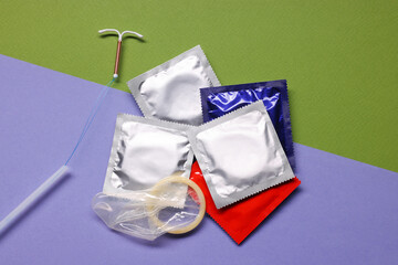 Condoms and intrauterine device on color background, flat lay. Choosing birth control method