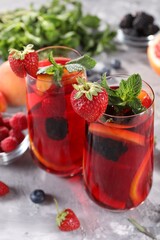 Delicious refreshing sangria and ingredients on light grey table, closeup