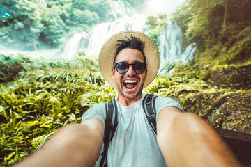 Happy traveler man with backpack taking selfie picture in the forest - Travel blogger taking self...