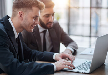 Fototapeta premium two professional businessmen discussing and using desktop computer in office