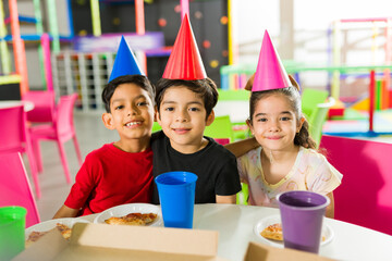 Group of kids with party hats during a birthday at the playroom
