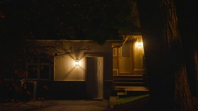 Establishing shot of two story stucco luxury house with garage door, big tree and nice landscape at night in Vancouver, Canada, North America. Night time on Apr 2023. ProRes 422 HQ.