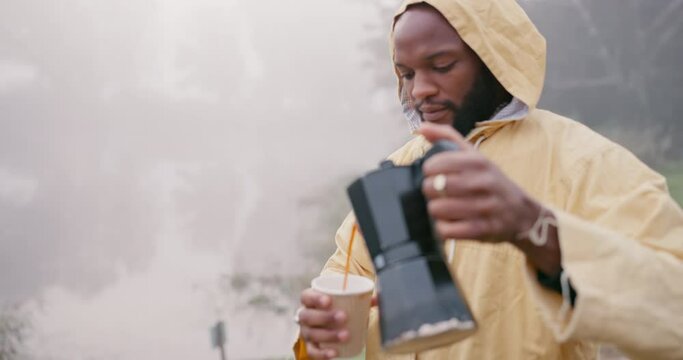 Black man, hiking and pour coffee in nature on vacation, holiday and travel outdoor in winter with fog. Tea, cup and African person preparing drink in the countryside, woods or forest with raincoat