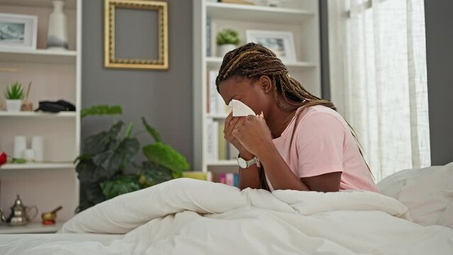 African american woman sitting on bed with being sick at bedroom