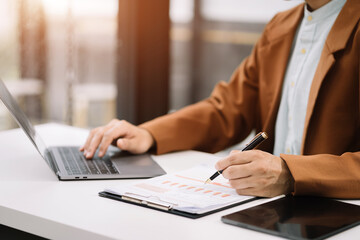 Businessman working at office with laptop and documents on his desk, financial adviser analyzing data.