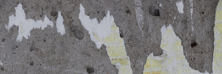 Torn old faded paper wallpaper with a retro pattern. Tattered scraps of paper on a concrete wall. Vintage texture for background and design. Closeup view with copy space.