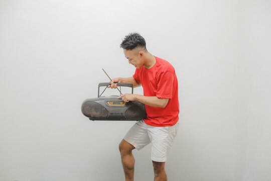 a young man wearing a red shirt on a white background is listening to the radio