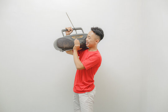 a young man wearing a red shirt on a white background is listening to the radio