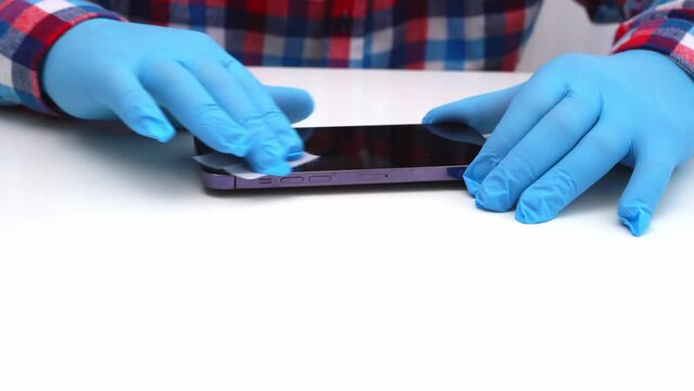 A male master glues a protective glass on a smartphone