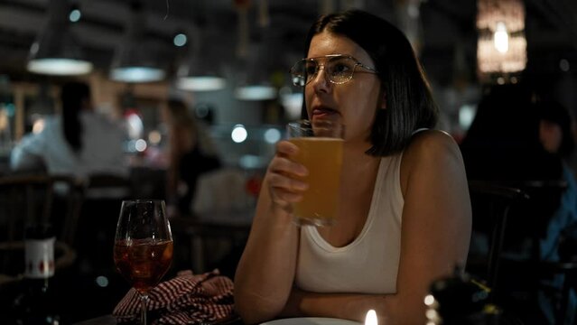 Young beautiful hispanic woman drinking beer at the restaurant