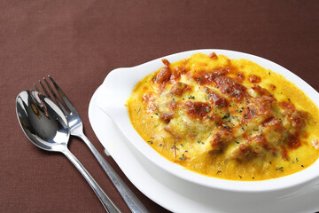 oven baked creamy cheese Japanese curry pasta fried rice with chicken seafood in bowl on brown cloth white background fork spoon western chef cuisine halal food menu for cafe