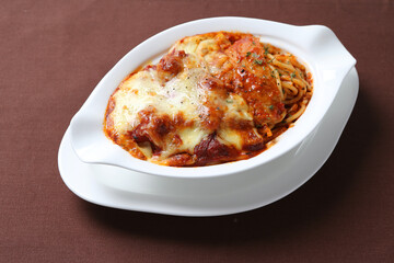 oven baked creamy cheese tomato Bolognese pasta noodle with grilled chicken chop seafood in bowl on brown cloth white background fork spoon western chef cuisine halal food menu for cafe
