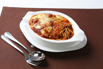 oven baked creamy cheese tomato Bolognese pasta noodle with grilled chicken chop seafood in bowl on brown cloth white background fork spoon western chef cuisine halal food menu for cafe