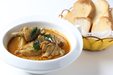 peranakan nonya spicy Malay curry leaf chicken and potato sauce in white bowl with baked french toast bread in bamboo basket on white background design asian chef cuisine halal food menu for cafe