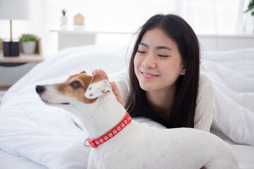 Beautiful young asian woman playful with fluffy dog for relax with love on bed in bedroom at home, friends pet with companion, friendship of woman and animal, female and friendly of puppy.