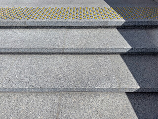 outdoors granite staircase with yellow nonskid bumpy markings on steps.