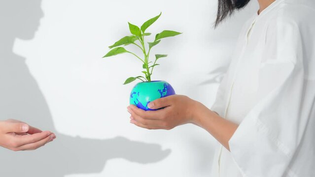 地球の描かれた植木鉢を受け渡す子供達　環境保護イメージ