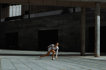 Sporty girl performs functional training on the street.