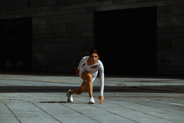 Sporty girl performs functional training on the street.