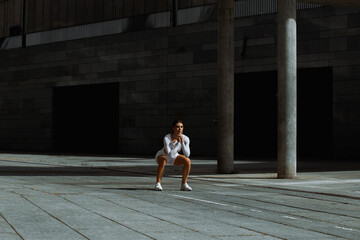 Sporty girl performs functional training on the street.