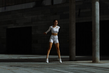 Sporty girl performs functional training on the street.