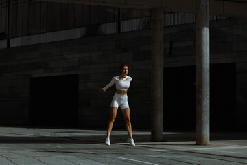 Sporty girl performs functional training on the street.