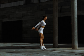 Sporty girl performs functional training on the street.