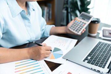 Businesswomen working to analyze, work together to discuss company financial statistics, brainstorm ideas, and graph documents on the table.