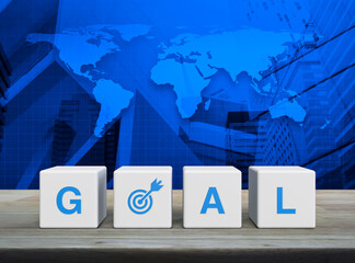 Goal icon on white block cubes on wooden table over world map, modern office city tower and skyscraper, Business success concept, Elements of this image furnished by NASA