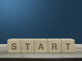Start letter on wood block cubes on wooden table over light blue wall, Business start up concept