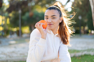 Young pretty brunette woman holding an orange