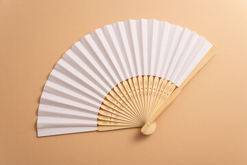 Folding traditional white hand fan for summer mock-up. Beige background