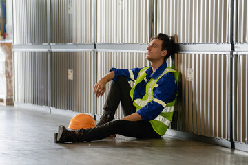 Tired sadly and bored manual worker sitting on the floor in a warehouse